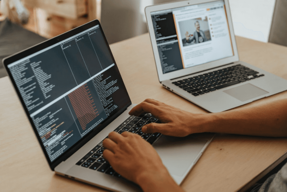 Persona programando en una laptop con código en pantalla
